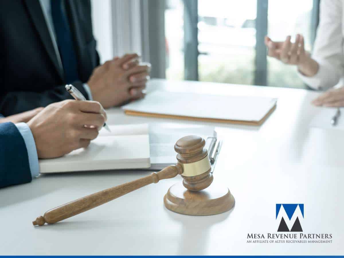 Business meeting discussing a client invoice, with legal documents, a gavel, and professionals taking notes at a conference table