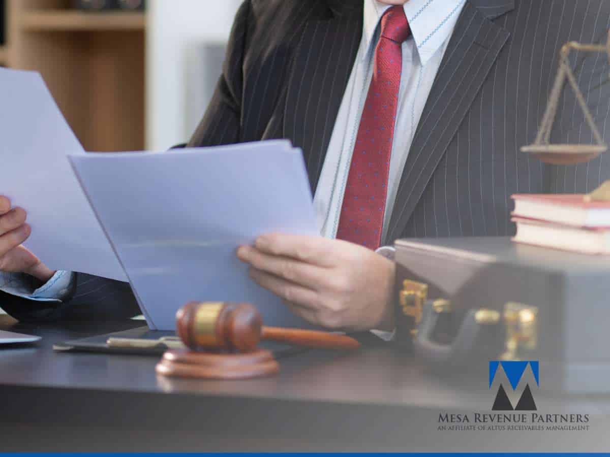 Lawyer reviewing documents related to the Debt Collection Process at a desk with gavel and briefcase.